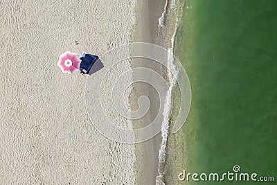 Beach umbrella alone on the seashore. Top view. Aerial View. Golden sand and green ocean waves. Bird eye view on the beach. Umbrel Stock Photo