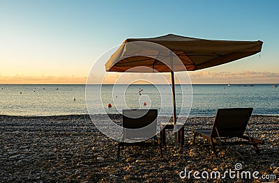 Beach umbrellas and relaxing chairs at sea at sunrise. Empty beach Pissouri Cyprus Stock Photo