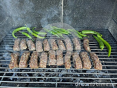 Mici and chilli peppers on barbeque - outdoor cooking Stock Photo