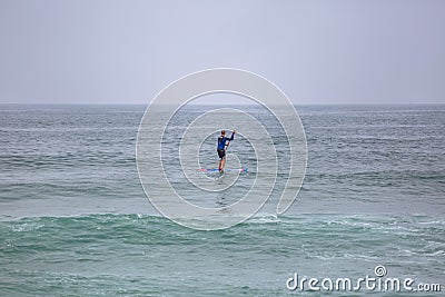 Beach view with professional Standup Paddleboarding doing extreme maneuvers in sea with waves Editorial Stock Photo