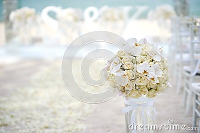 A bunch of white cream roses, orchids on the glass vase beside the aisle at the beach wedding ceremony - closed up Stock Photo