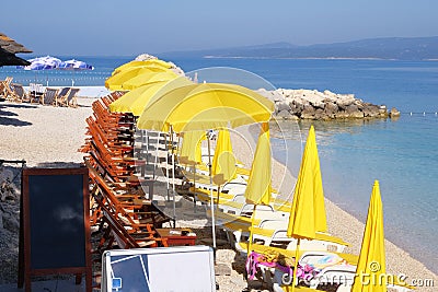 Beach yellow umbrellas and chaise for relax and comfort on sea coast. Happy summer vacations and tourism concept. Paid service on Stock Photo