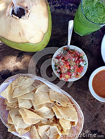 Beachside meal in Mexico: corn chips, salsa, coconut, green juice Stock Photo