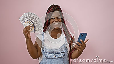 Beaming african american woman flaunting dollar bills with phone over pink isolated background - a winner in online betting Stock Photo