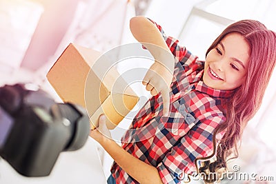 Beaming dark-haired birthday girl filming her funny blog about presents Stock Photo