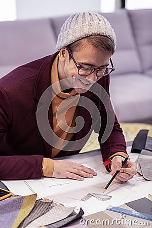 Beaming mature male creator making drawings siting at the table Stock Photo