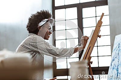 Beaming international art student sitting near window and painting Stock Photo