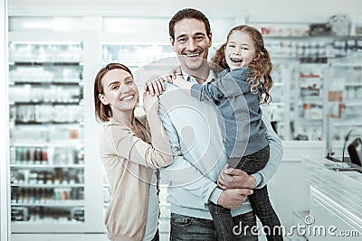 A beamingly smiling family sharing cuddles near the pharmacy checkout Stock Photo