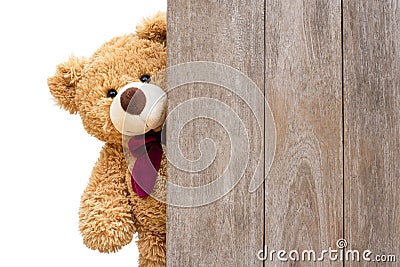 Teddy bear sneaked behind the old wooden door isolated on white Stock Photo