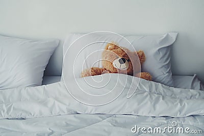 A bear doll laying on white bed. Stock Photo