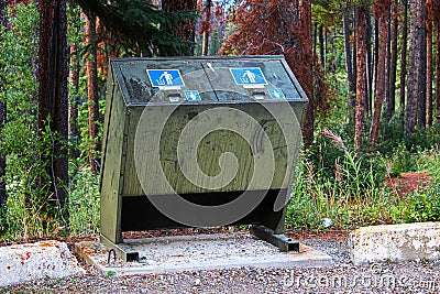 A bear proof garbage container along side a parking lot Stock Photo