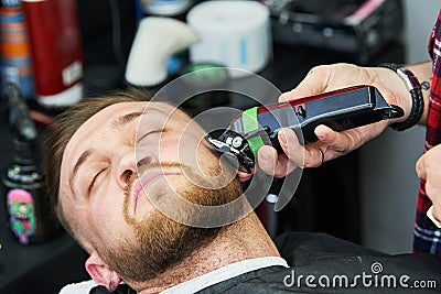 Beard care. man while trimming his facial hair cut at the barbershop Stock Photo