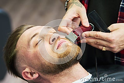 Beard care. man while trimming his facial hair cut at the barbershop Stock Photo