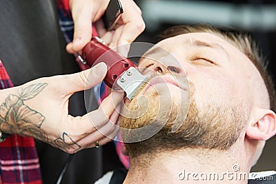 Beard care. man while trimming his facial hair cut at the barbershop Stock Photo