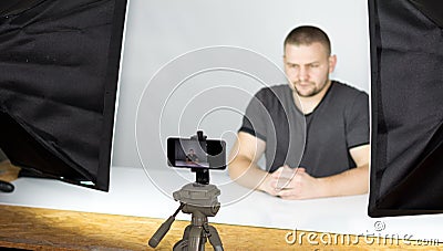 Bearded attractive male video blogger shoots video streaming for users while Stock Photo