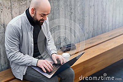 Bearded businessman freelancer working on laptop outdoors. Man typing on laptop keyboard. Remote work, online marketing Stock Photo