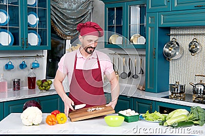 Bearded Chef in cap holds cutting wooden board in hands Stock Photo