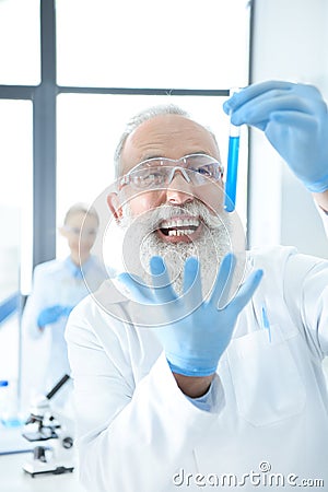 Bearded chemist holding test tube with reagent and gesturing Stock Photo