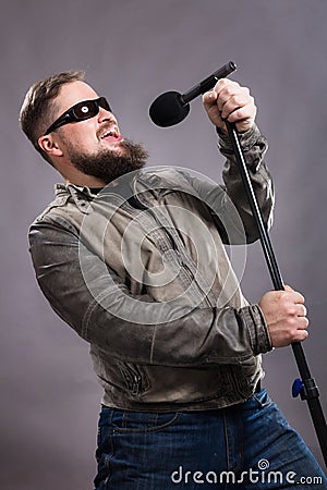 Bearded emotional rock singer with microphone studio portrait. Stock Photo