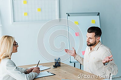 Bearded employee showing shrug gesture near attractive recruiter Stock Photo