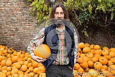 Bearded farmer with pumpkin on a background of a pile of pumpkins Stock Photo