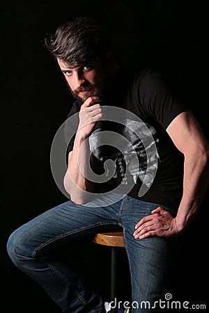 Bearded guy sitting on a bar stool and holding his chin . Close.up. Black Stock Photo