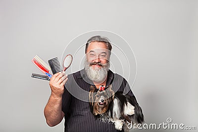 bearded hairdresser for dogs with combs and a terrier on his hands Stock Photo