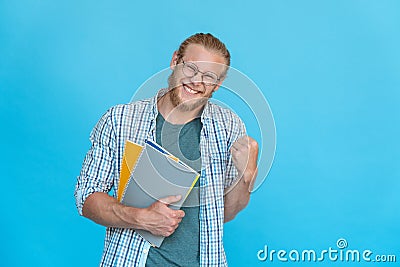 Bearded happy excited student in glasses hold copybooks yes victory gesture Stock Photo