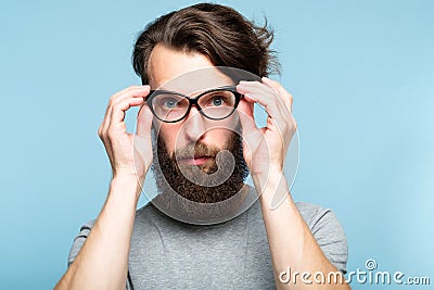 Bearded hipster fixing cat eye glasses geeky man Stock Photo