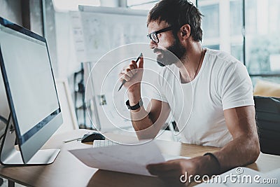 Bearded hipster professional wearing eye glasses working at modern loft studio-office with desktop computer.White blank Stock Photo