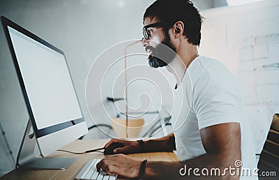 Bearded hipster professional wearing eye glasses working at modern loft studio-office with desktop computer.White blank Stock Photo