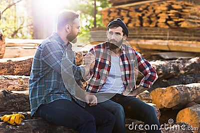 bearded lumberjacks sitting on logs and shaking hands Stock Photo