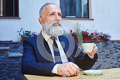 Bearded male drinking coffee while sitting Stock Photo
