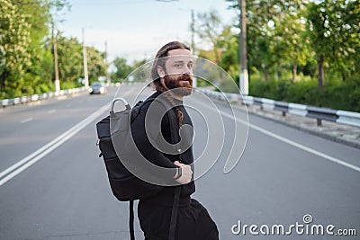Bearded man in black clothes jaywalking. Dangerous crossing the road Stock Photo