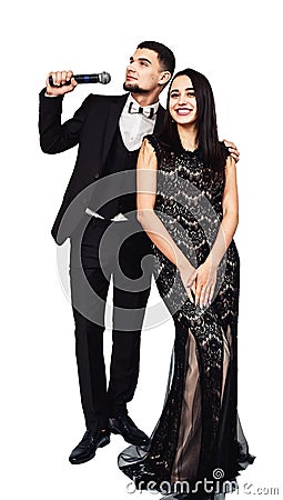 Bearded man in a black suit with a microphone in his hand and a pretty girl in a black evening dress Stock Photo