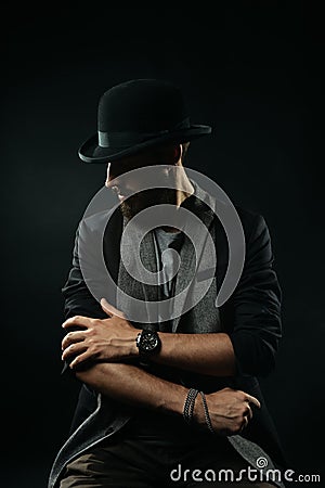 The bearded man in bowler hat rolls up sleeves of his jacket Stock Photo