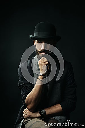 The bearded man in a bowler hat touching his beard Stock Photo