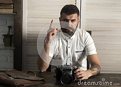 Bearded man with camera and raised finger up at desk Stock Photo