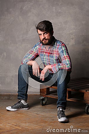 Bearded man in colorful shirt sitting on a deck Stock Photo