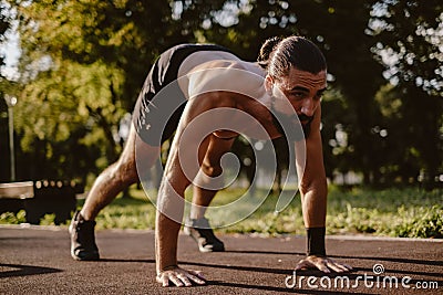 Man doing dive bomber push ups in the outdoor gym Stock Photo