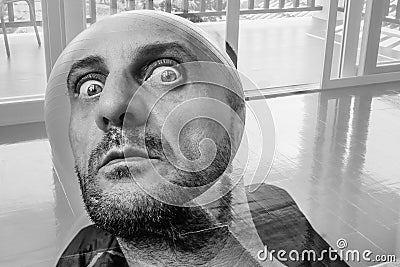 Bearded man with dramatic big eyes watching you, terrific portrait of tormented man with head in the form of balloon Stock Photo