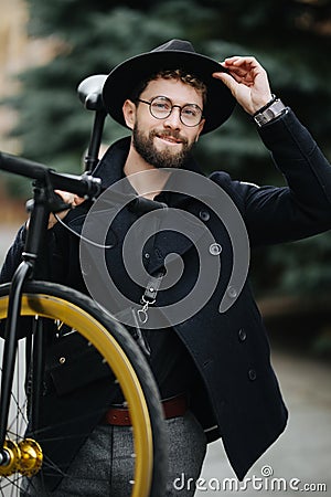 Bearded man with fixie bicycle. Low angle view of confident young bearded man carrying his bicycle on shoulder and looking away Stock Photo