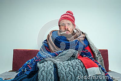 Bearded Man with Flue Sitting on Sofa at Home. Healthcare Concepts. Stock Photo