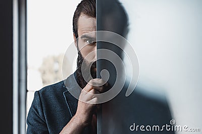 Bearded man hiding by frosted glass Stock Photo