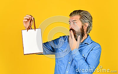 Bearded man hold paper bag. presents. delighted man shopping online. surprised hipster making purchases at electronics Stock Photo