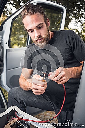 Man inside a van using heat shrink tubing on a electrical cable Stock Photo