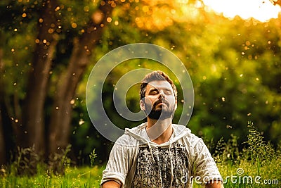 A bearded man is meditating on green grass in the park Stock Photo