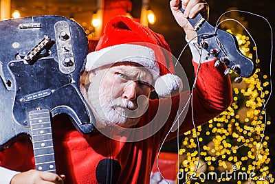 Bearded man in Santa costume with broken Electric guitar. Musical instrument. Rock guitarist. New year. Christmas time. Stock Photo