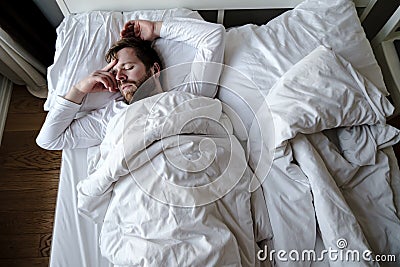 Bearded man sleeps restlessly in bed, he is alarmed and had a terrible nightmare. Stock Photo