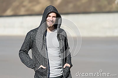 Bearded man smile in hood on sunny outdoor, fashion. Macho happy smiling in sweatshirt, casual style. Mens fashion, style, sportsw Stock Photo